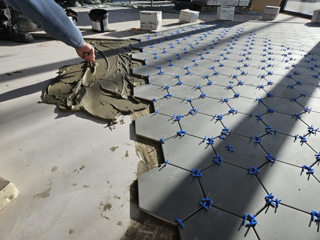 Pose du carrelage hexagonal dans la future boutique AUX 3 CHOUX à Saint-Amand-Montrond lors des travaux d’aménagement.