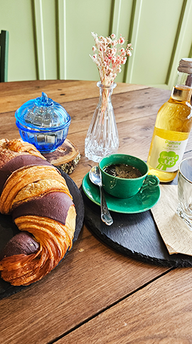 photo de présentation au salon de thé du jeudi viennoiserie en folie avec un gros croissant au chocolat et un café dans une ambiance châleureuse