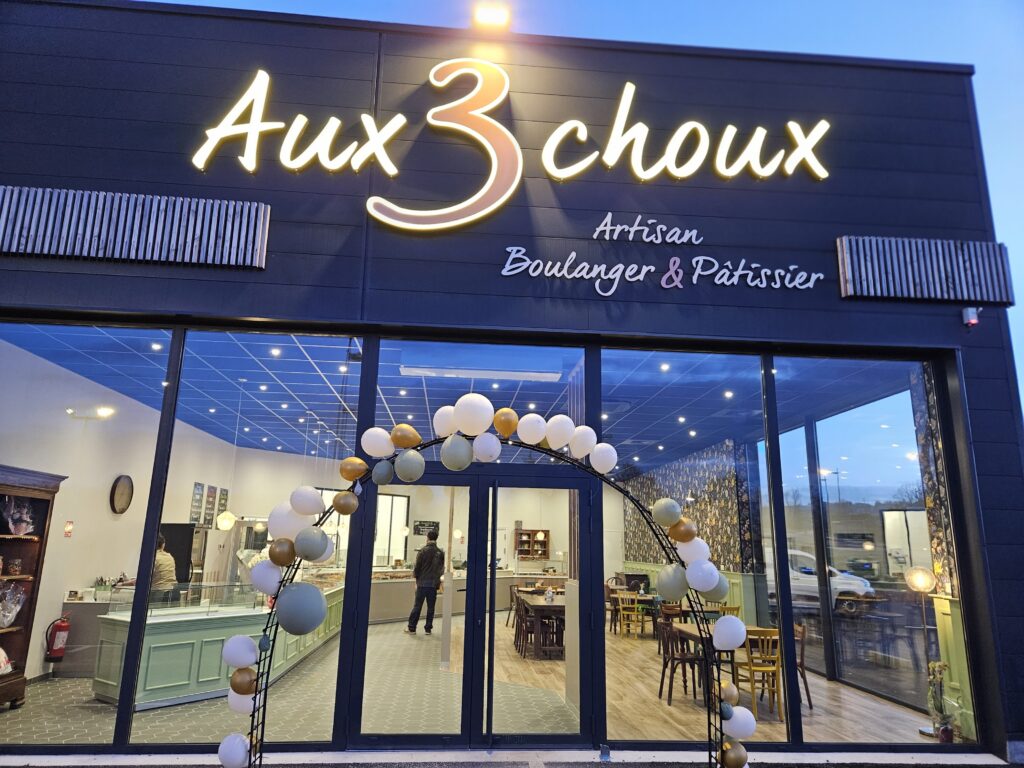 Façade de la nouvelle boulangerie Aux 3 Choux illuminée le soir avant l’ouverture du second point de vente à Saint-Amand-Montrond.