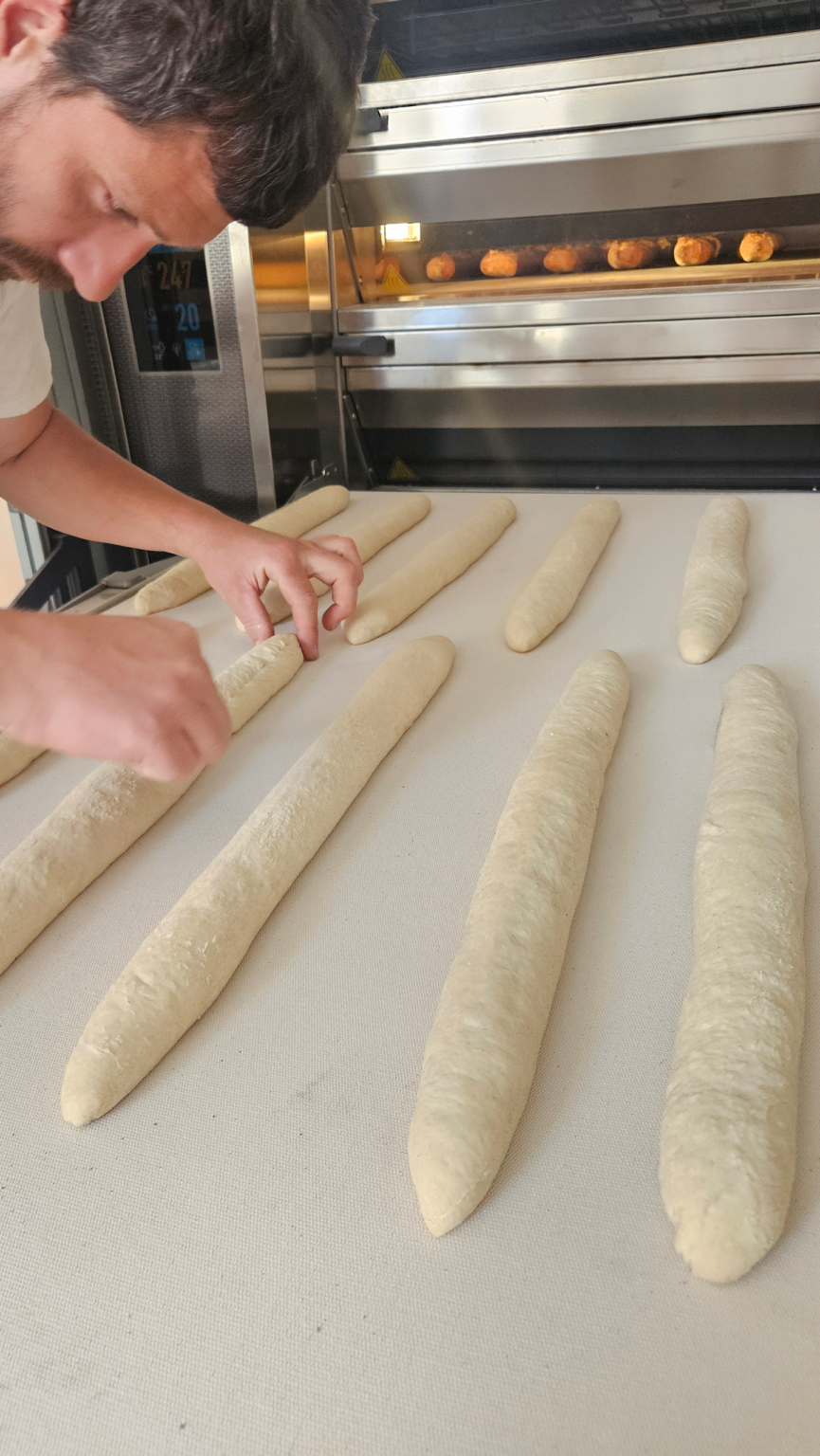 Artisan boulanger façonnant des baguettes avant cuisson dans le fournil AUX 3 CHOUX à Saint-Amand-Montrond